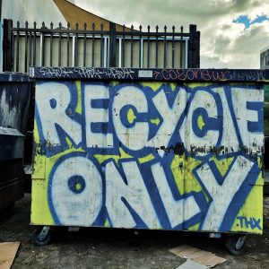 a dumpster covered in graffiti next to a building